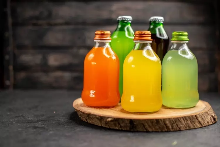 jugos vista frontal diferentes colores botellas sobre tablero madera sobre superficie madera oscura 58fa0